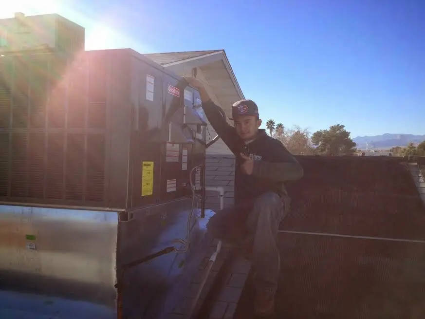 HVAC technician performing AC Tune-Up on a rooftop unit in Rochester